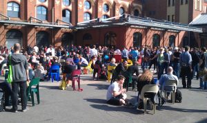 Der sonnenüberflutete Innenhofder Station mit hunderten Teilnehmern auf Plastikstühlen