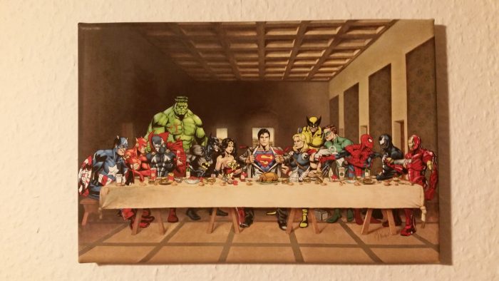 13 Comichelden von DC und Marvel sind wie zum letzten Abendmahl arrangiert.
